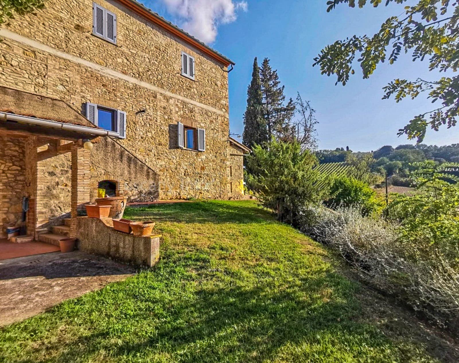 Restored stone Tuscan farmhouse with garden and vineyard view